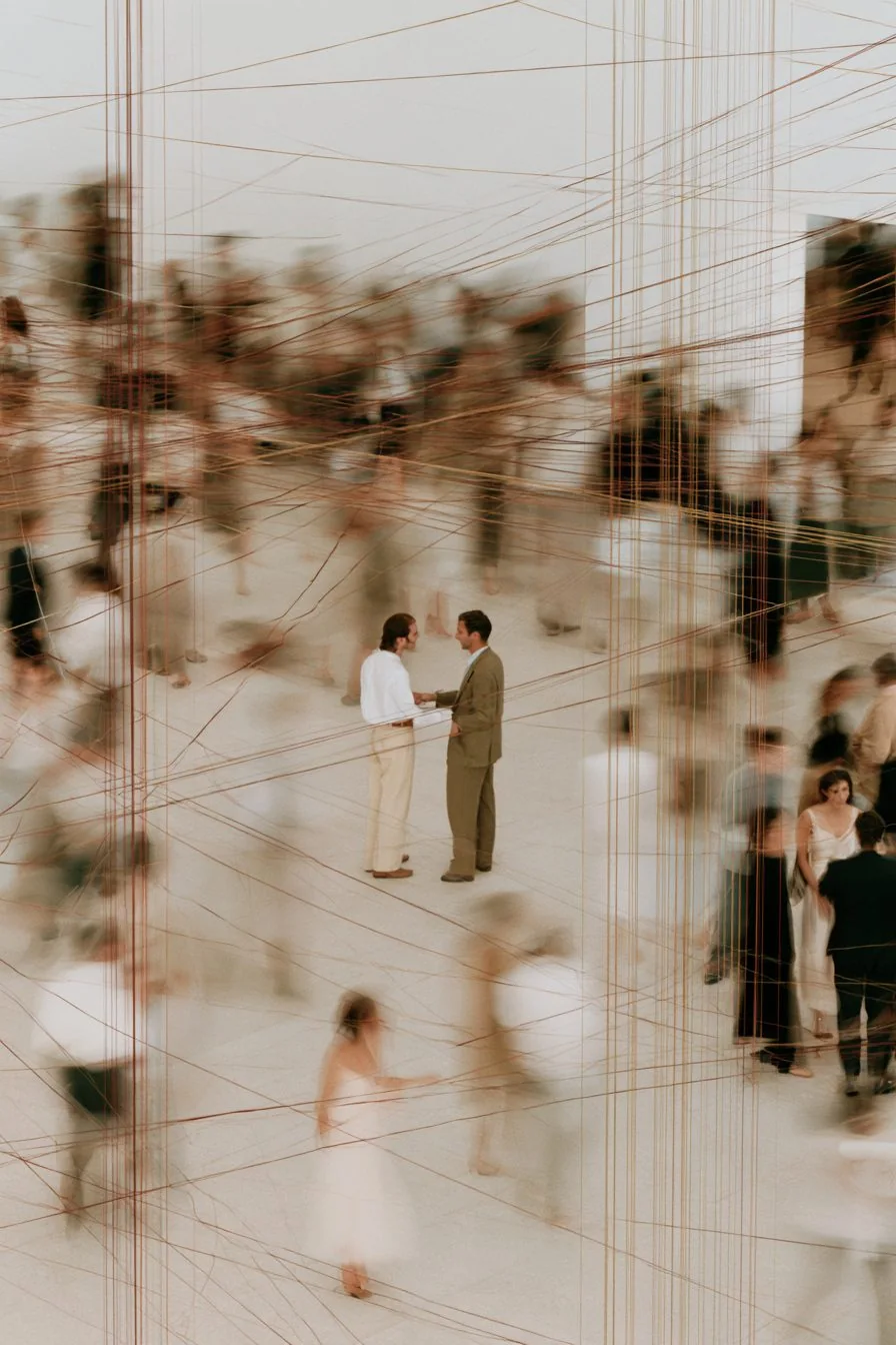 Two members shaking hands beneath gold threads